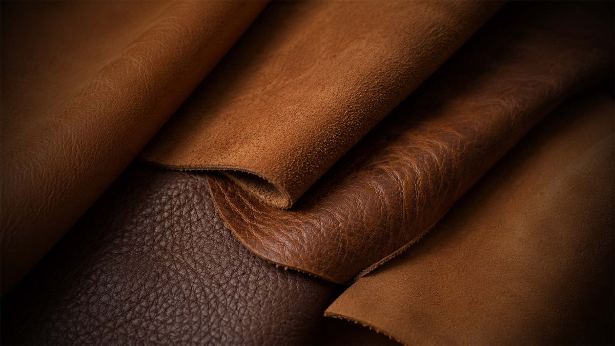 Close-up of layered leather material in warm brown tones, including smooth tan, medium brown, and darker brown pebbled leather textures.